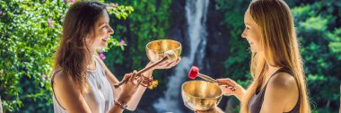 Banner, Uzun Format Nepal Buda bakır spa salonunda kase şarkı kase. Genç güzel kadın bir şelale karşı Spa'da şarkı kase masaj terapisi yapıyor. Ses terapisi, rekreasyon, meditasyon