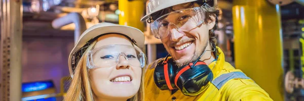 Muž a žena ve žluté pracovní uniformě, brýle a helmici v průmyslovém prostředí, ropná plošina nebo zařízení na zkapalněný plyn nápis, dlouhý formát — Stock fotografie