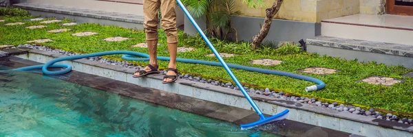 Cleaner of the swimming pool . Man in a blue shirt with cleaning equipment for swimming pools. Pool cleaning services BANNER, LONG FORMAT