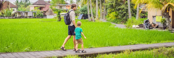 Dad and son travelers on Beautiful Rice Terraces against the background of famous volcanoes in Bali, Indonesia Traveling with children concept BANNER, LONG FORMAT