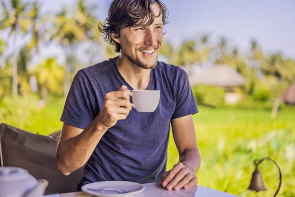 Homem com uma xícara de chá na varanda do café perto dos terraços de arroz em Bali, Indonésia — Fotografia de Stock