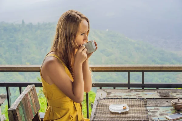 Молода жінка п'є каву в кафе в горах — стокове фото