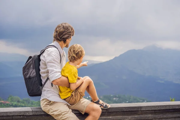 Papà e figlio turisti sullo sfondo guardando il vulcano Batur. Indonesia. Viaggiare con il concetto di bambini — Foto Stock