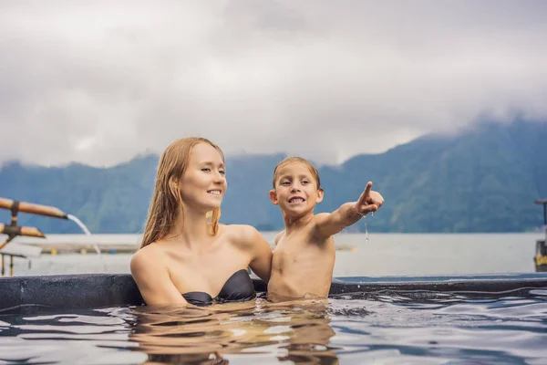 Mamma e figlio viaggiatori a Hot Springs a Bali sullo sfondo del lago. Viaggiare con i bambini concetto — Foto Stock