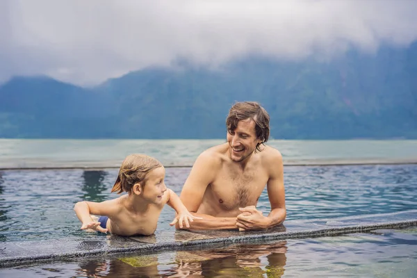 Otec a syn cestující v horkých pramenů na Bali na pozadí jezera. Koncepce cestování s dětmi — Stock fotografie