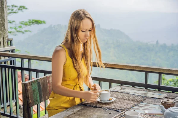 Молодая женщина пьет кофе в кафе в горах — стоковое фото