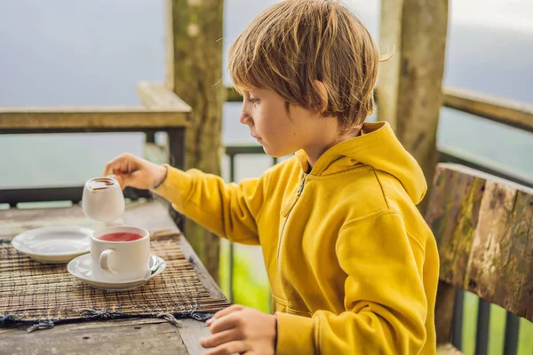 Мальчик пьет чай в кафе в горах — стоковое фото