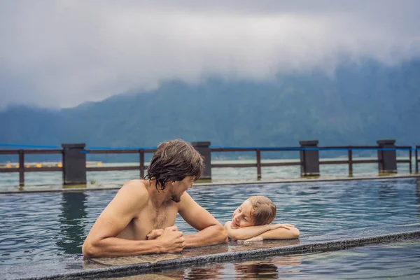 Papà e figlio viaggiatori a Hot Springs a Bali sullo sfondo del lago. Viaggiare con i bambini concetto — Foto Stock