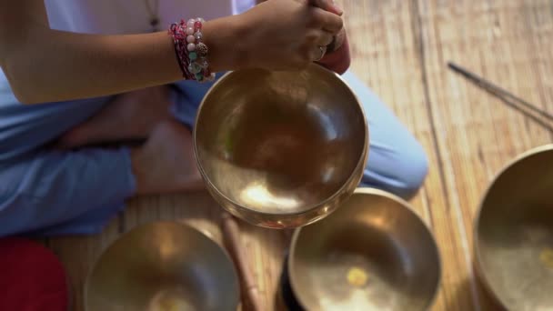 Superslowmotion skott av en kvinna mästare i asiatisk helig medicin utför tibetanska skålar helande ritual. Meditation med tibetanska sjungande skålar. Hon sitter i ett lusthus för meditation med en vacker — Stockvideo