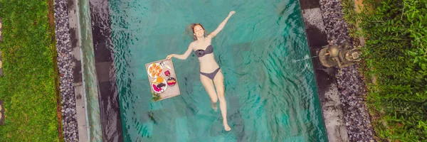 BANNER, LONG FORMAT Plateau de petit déjeuner dans la piscine, petit déjeuner flottant dans un hôtel de luxe. Fille se détendre dans la piscine en buvant des smoothies et en mangeant une assiette de fruits, smoothie bol près de la piscine de l'hôtel. Exotique — Photo