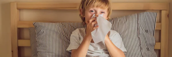 Chory chłopiec kaszel i chusteczki nos z chusteczki. Chorego dziecka z gorączką i chorobą w łóżku banner, Long format — Zdjęcie stockowe