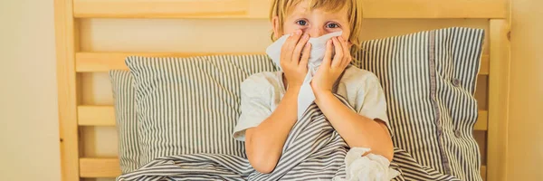 Chory chłopiec kaszel i chusteczki nos z chusteczki. Chorego dziecka z gorączką i chorobą w łóżku banner, Long format — Zdjęcie stockowe