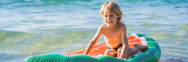 Το αγόρι κολυμπάει στη θάλασσα σε ένα φουσκωτό στρώμα πανό, Long Format — Φωτογραφία Αρχείου