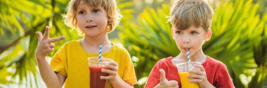 Banner, Uzun Format İki erkek palmiye ağaçlarının fon karşı sağlıklı smoothies içmek. Mango ve karpuz smoothies. Çocuklar için sağlıklı beslenme ve vitaminler
