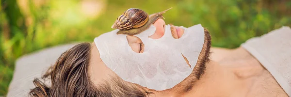 Ung man gör en ansiktsmask med snigel slem. Snigel kryper på en ansiktsmask. Spa för man, Spa för alla banner, lång format — Stockfoto