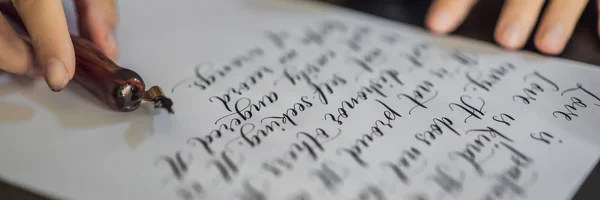 Skládaný, dlouhý formát Kalligrafka ruce píše frázi na bílém papíře. Biblická fráze o lásce to jsou ozdobná ozdobná písmena. Kaligrafie, grafická konstrukce, písmo, rukopis, tvorba — Stock fotografie