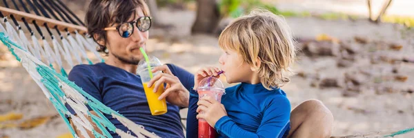 Pai e filho se divertindo em uma rede com uma bebida BANNER, LONG FORMAT — Fotografia de Stock