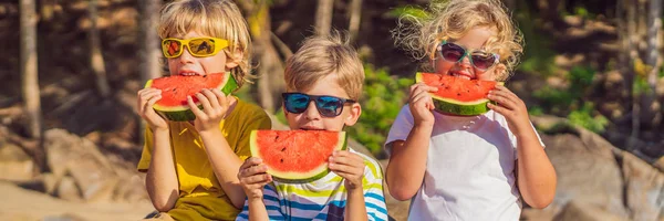 Діти їдять кавун на пляжі в сонцезахисних окулярах BANNER, LONG FORMAT — стокове фото