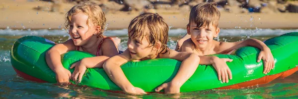 I bambini nuotano in mare su un materasso gonfiabile e si divertono BANNER, FORMATO LUNGO — Foto Stock
