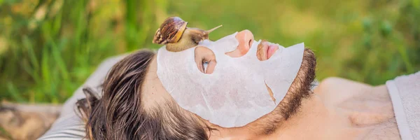 Young man makes a face mask with snail mucus. Snail crawling on a face mask. SPA for man, SPA for all BANNER, LONG FORMAT