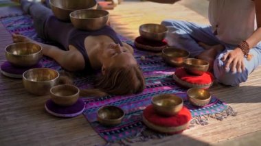 Asya kutsal tıp bir kadın ustası Superslowmotion atış bir müşteri genç kadın için Tibet kase şifa ritüel gerçekleştirir. Tibet şarkı kaseleri ile Meditasyon. Onlar için bir çardak bulunmaktadır