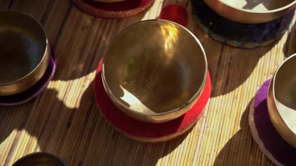 Superslowmotion skott av en kvinna mästare i asiatisk helig medicin utför tibetanska skålar helande ritual. Meditation med tibetanska sjungande skålar. Hon sitter i ett lusthus för meditation med en vacker — Stockvideo
