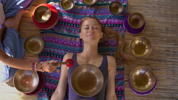 Superslowmotion disparo de una mujer maestra de la medicina sagrada asiática realiza cuencos tibetanos ritual de curación para una joven cliente. Meditación con cuencos tibetanos. Están en un mirador para — Vídeos de Stock