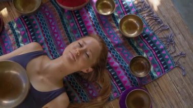 Asya kutsal tıp bir kadın ustası Superslowmotion atış bir müşteri genç kadın için Tibet kase şifa ritüel gerçekleştirir. Tibet şarkı kaseleri ile Meditasyon. Onlar için bir çardak bulunmaktadır