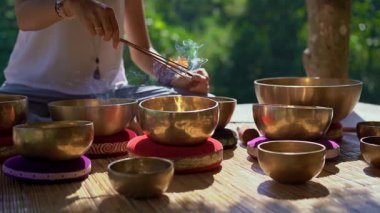 Asya kutsal tıp bir kadın ustası Superslowmotion atış Tibet kase şifa ritüel gerçekleştirir. Tibet şarkı kaseleri ile Meditasyon. O güzel bir meditasyon için bir çardak oturur
