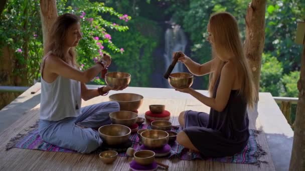 亚洲圣医女大师的超慢动作镜头，为一位女青年表演藏碗疗伤仪式。用藏语唱碗冥想。他们在凉亭 — 图库视频影像