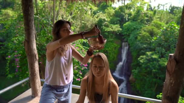 Superslowmotion scatto di una donna maestro di medicina sacra asiatica esegue ciotole tibetane rituale di guarigione per una giovane donna cliente. Meditazione con ciotole tibetane. Sono in un gazebo per — Video Stock