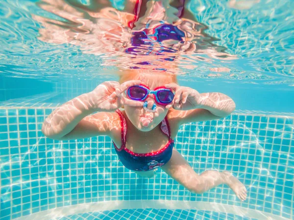 La niña en el parque acuático nadando bajo el agua y sonriendo — Foto de Stock