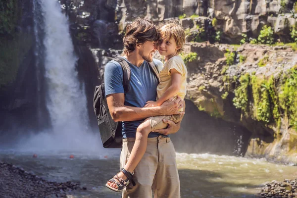 Dad and son tourists on the background of a waterfall. Traveling with kids concept. What to do with children Children friendly place