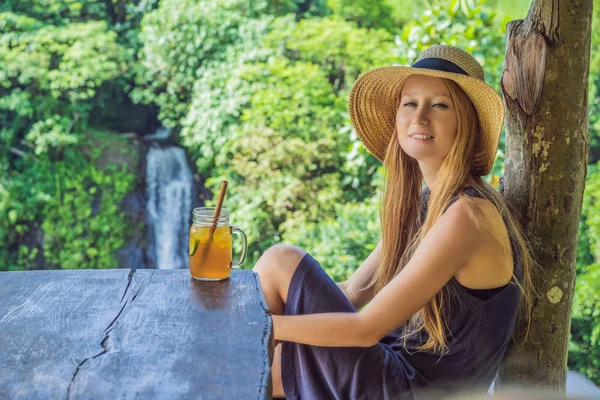 Nahaufnahme Portraitbild einer schönen Frau trinkt Eistee mit Glücksgefühl in der grünen Natur und Wasserfall Garten Hintergrund — Stockfoto