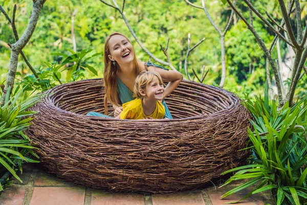 Bali trend, straw nests everywhere. Happy family enjoying their travel around Bali island, Indonesia. Making a stop on a beautiful hill. Photo in a straw nest, natural environment. Lifestyle