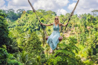 Endonezya'nın Bali adasının orman yağmur ormanlarında sallanan genç bir kadın. Tropik lerde salıncak. Swings - Bali trendi