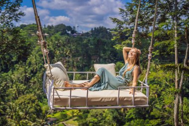 Endonezya'nın Bali adasının orman yağmur ormanlarında sallanan genç bir kadın. Tropik lerde salıncak. Swings - Bali trendi