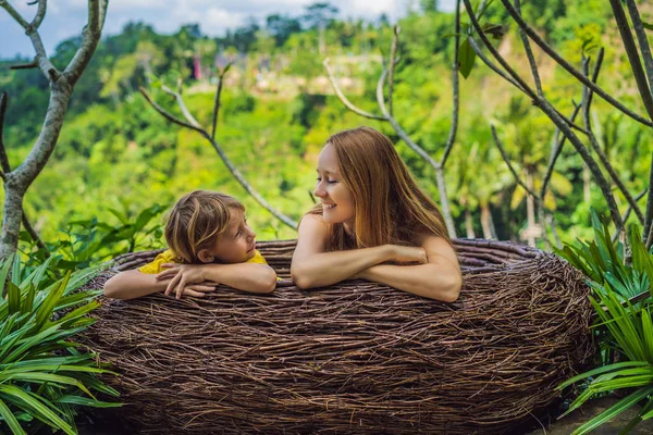 Bali trend, straw nests everywhere. Happy family enjoying their travel around Bali island, Indonesia. Making a stop on a beautiful hill. Photo in a straw nest, natural environment. Lifestyle