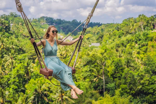 Молодая женщина, раскачивающаяся в джунглях тропического леса острова Бали, Индонезия. Качели в тропиках. Качели - тренд Бали — стоковое фото