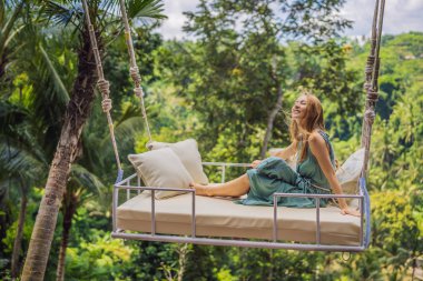 Endonezya'nın Bali adasının orman yağmur ormanlarında sallanan genç bir kadın. Tropik lerde salıncak. Swings - Bali trendi