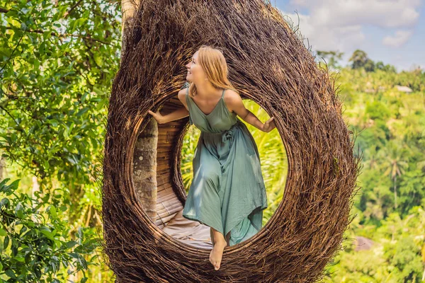 Bali trend, straw nests everywhere. Young tourist enjoying her travel around Bali island, Indonesia. Making a stop on a beautiful hill. Photo in a straw nest, natural environment. Lifestyle