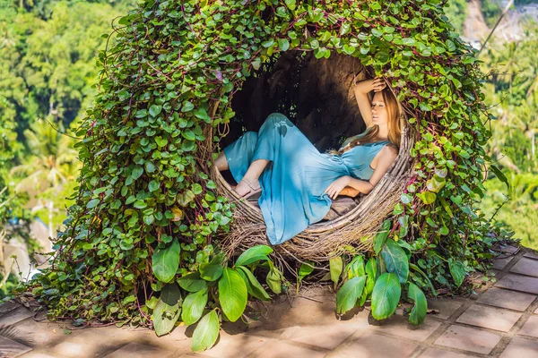 Bali trend, straw nests everywhere. Young tourist enjoying her travel around Bali island, Indonesia. Making a stop on a beautiful hill. Photo in a straw nest, natural environment. Lifestyle