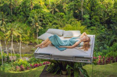 Genç bir kadın ormanın üzerinde yatakta. Doğaile samimiyet