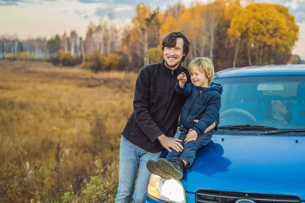 Papà e figlio stanno riposando sul ciglio della strada durante un viaggio. Viaggio con bambini concetto — Foto Stock