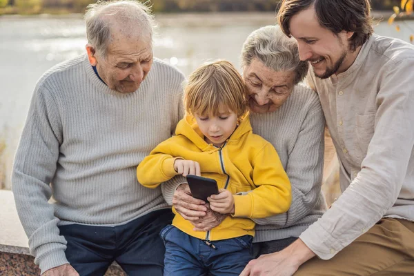 O menino mostra a foto no telefone para seus avós — Fotografia de Stock