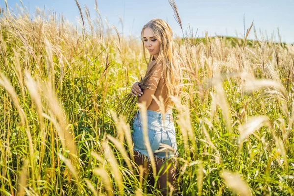 Junge schöne Frau in herbstlicher Landschaft mit trockenen Blumen, Weizenspitzen. Mode Herbst, Winter. sonniger Herbst, Modefoto — Stockfoto