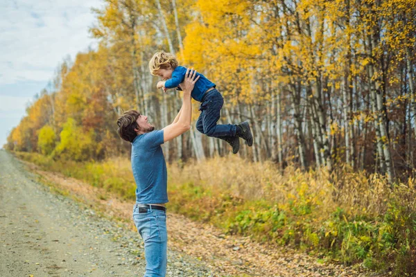 Papà gioca con suo figlio sullo sfondo della foresta autunnale — Foto Stock