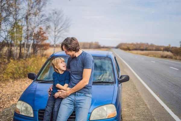 Papá e hijo están descansando al lado de la carretera en un viaje por carretera. Viaje por carretera con concepto de niños — Foto de Stock