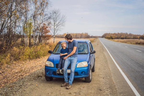 Papà e figlio stanno riposando sul ciglio della strada durante un viaggio. Viaggio con bambini concetto — Foto Stock