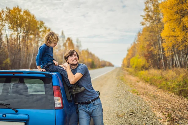 Papà e figlio stanno riposando sul ciglio della strada durante un viaggio. Viaggio con bambini concetto — Foto Stock